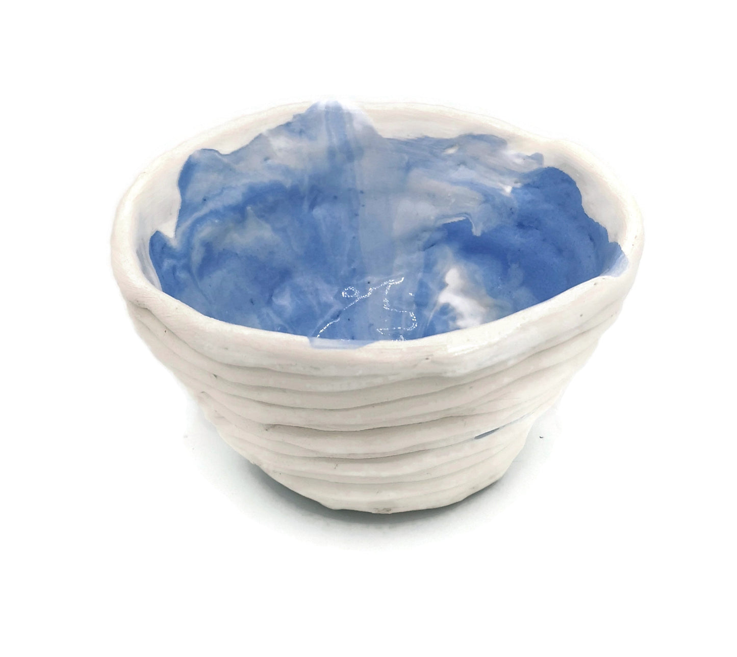 A handmade ceramic bowl with a blue interior and a white exterior. The bowl has an irregular, textured shape and is shown with a small amount of blue glaze detailing.