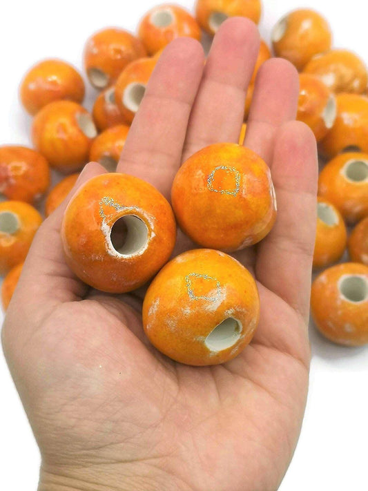 large ceramic beads, orange, standing on a hand